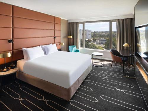 una habitación de hotel con una cama y una ventana grande en Mercure Sydney Parramatta, en Sídney
