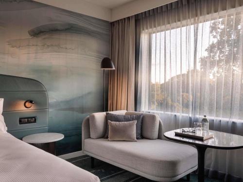 una camera da letto con divano, tavolo e finestra di Novotel Tainui Hamilton a Hamilton