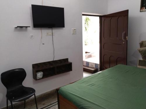 Un dormitorio con una cama y una silla y un televisor. en Hotel vishram, en Aligarh