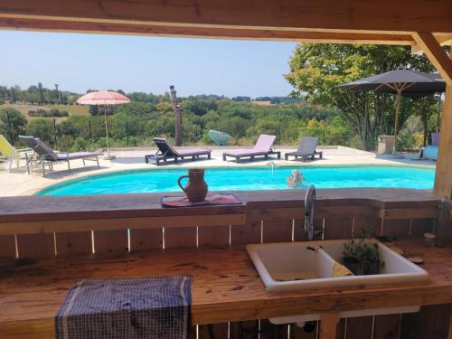 a kitchen with a sink and a swimming pool at LA P'TITE MAIZ in Bourg-de-Visa