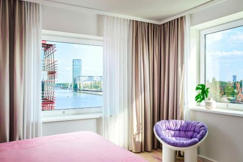 a bedroom with a purple chair and a window at nhow Berlin in Berlin
