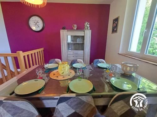 a dining room with a table and a clock on the wall at La Maison d'à côté in Taussac