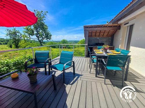 a deck with a table and chairs and an umbrella at La Maison d'à côté in Taussac