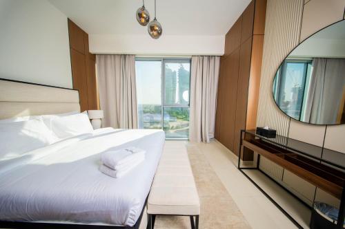 a bedroom with a large white bed and a mirror at Luxury 1 Bedroom Canalfront Apartment with Burj Khalifa Views from Resort-Style Pool - Walk to Jumeirah Beach in Dubai