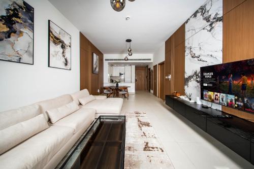 a living room with a white couch and a tv at Luxury 1 Bedroom Canalfront Apartment with Burj Khalifa Views from Resort-Style Pool - Walk to Jumeirah Beach in Dubai