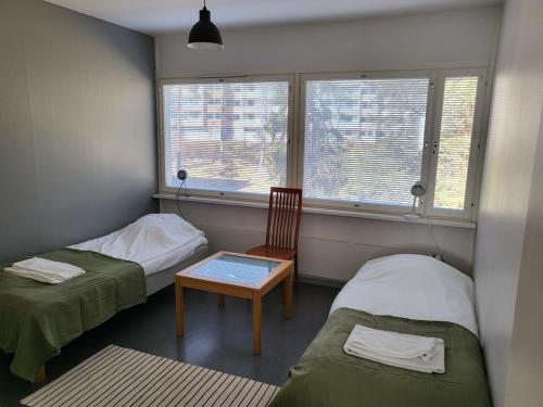 um quarto com duas camas e uma cadeira e uma janela em Kotimaailma - kolmio Kotkasta em Kotka