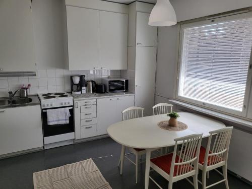 uma cozinha com uma mesa e cadeiras e um fogão e lavatório em Kotimaailma - kolmio Kotkasta em Kotka