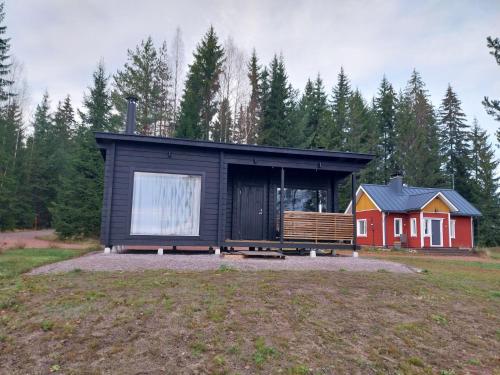 a tiny house in a field next to a forest at VillaTorppa in Jämsä