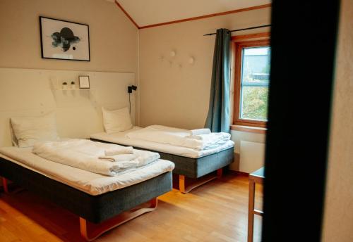 two beds in a small room with a window at Lødingen Brygge in Lødingen