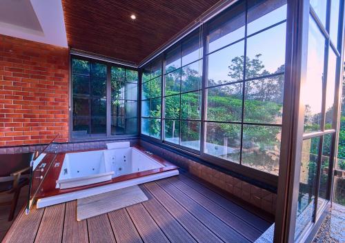 a bath tub in a room with windows at The Saray Munnar by VOYE HOMES in Anachal