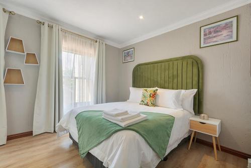 une chambre avec un grand lit avec une tête de lit verte dans l'établissement Modern Family Haven with Garden Sleeps 8, à Sandton