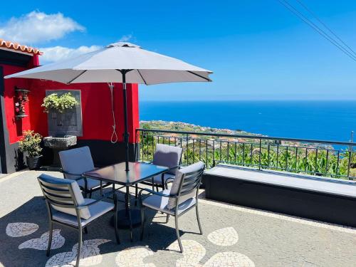 a table and chairs with an umbrella on a balcony at Studio Refúgio in Ponta do Sol