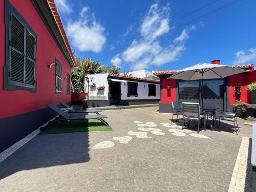 a patio with a table and an umbrella next to a building at Studio Refúgio in Ponta do Sol