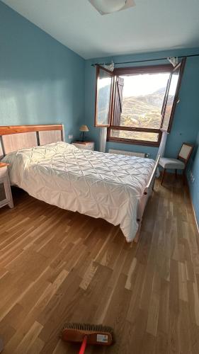 ein Schlafzimmer mit einem Bett mit Fenster und Holzboden in der Unterkunft Formigal Valle del tena Rural Home in Formigal