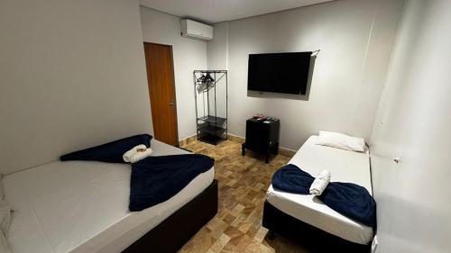 a bedroom with two beds and a tv on the wall at Riacho Hotel in Brasilia