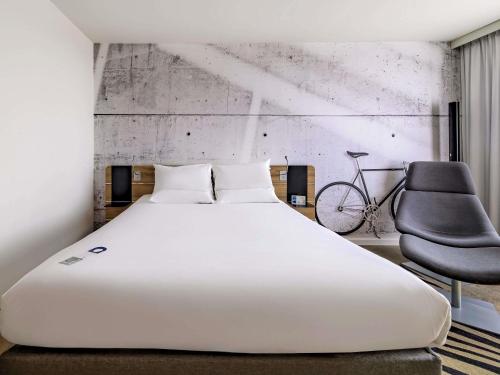 Un dormitorio con una gran cama blanca y una silla. en Novotel Kraków Centrum, en Cracovia