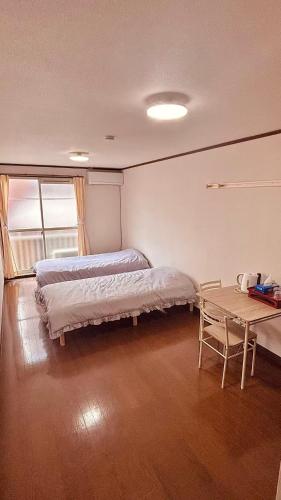 ein Schlafzimmer mit zwei Betten und einem Tisch darin in der Unterkunft About 10 minutes to Fukuoka University Station 20 minutes to Tenjin hakata by subway in Fukuoka