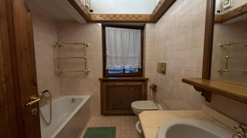 een badkamer met een bad, een toilet en een wastafel bij Mansarda Ca Geranei in San Vito di Cadore