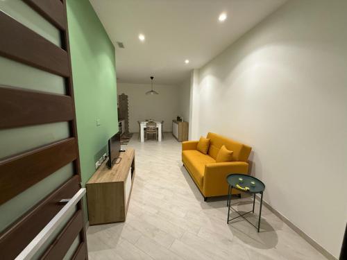 a living room with a yellow couch and a table at Maison Rovaga in Ispica