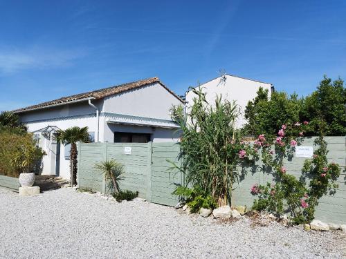 a house with a green fence and flowers at La pointe du Chay in Angoulins-sur-Mer