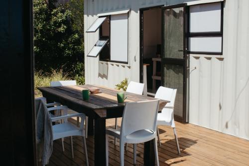 ein Holztisch und weiße Stühle auf einer Terrasse in der Unterkunft Mountain Magic Hoekwil in Wilderness