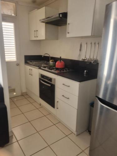 a kitchen with white cabinets and a stove top oven at Departamento elsa ramitez in Ovalle