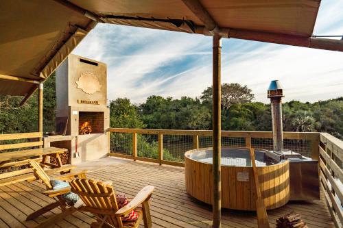 a deck with a hot tub and a fireplace at AfriCamps at Bonamanzi Game Reserve in Hluhluwe