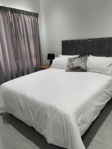 1 cama blanca grande con sábanas y almohadas blancas en Atloch, en Kimberley