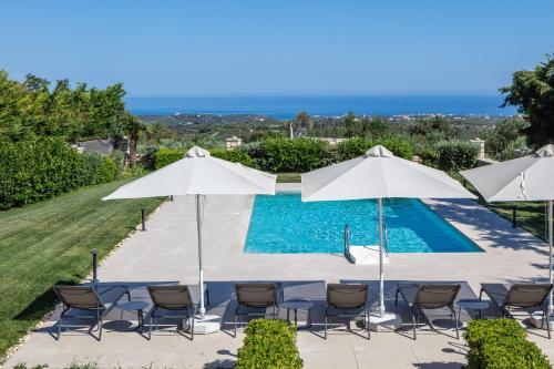 a swimming pool with chairs and umbrellas at Ferienvilla Malvasia Mit Swimmingpool Auf Kreta in Roúpai