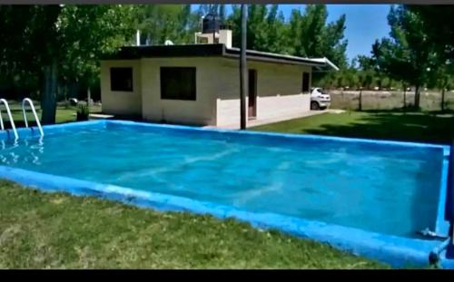 una piscina azul en un patio con una casa en Villa Carrizal, en Ciudad Lujan de Cuyo