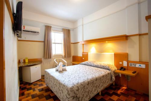 a hotel room with a bed and a television at Oscar Hotel in Florianópolis