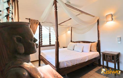 a bedroom with a canopy bed with a statue at Kisiwa Apartments Watamu - At Ascot Resort - in Watamu