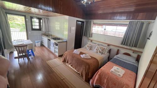 a small bedroom with a bed and a kitchen at Chalés Ipe Amarelo in Camanducaia