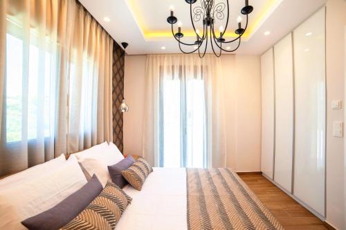 a bedroom with a large white bed with a chandelier at Perla Nera Villa Mit Privatem Beheiztem Pool in Kávallos