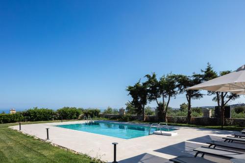 a swimming pool with chairs and an umbrella at Ferienvilla Malvasia Mit Swimmingpool Auf Kreta in Roúpai
