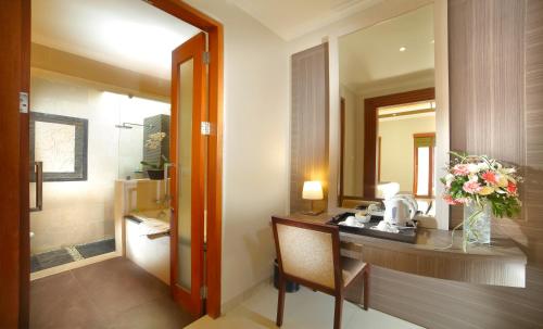 a bathroom with a vanity with a vase of flowers at The Banyumas Suite Villa Legian in Legian