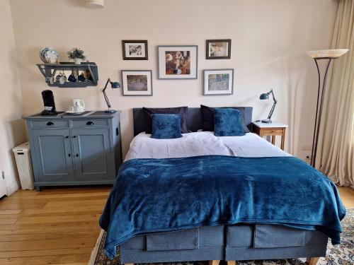 a bedroom with a bed with blue sheets and pictures on the wall at Gastsuite in Valkenburg aan de Geul in Valkenburg