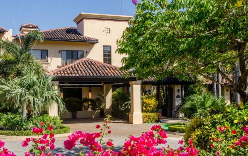 普拉卡海尔Casa Serena Luxury Retreat in Reserva Conchal的前面有粉红色花的房子