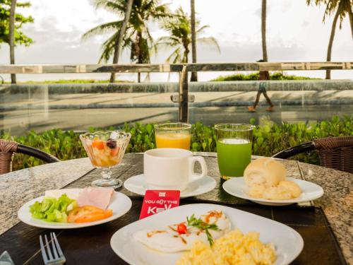 ein Tisch mit Tellern mit Essen und Getränken darauf in der Unterkunft Ibis Joao Pessoa Praia in João Pessoa