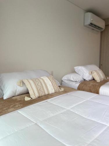 圣玛尔塔Frente al mar ,vista panoramica, acceso a la playa的房间里有两张床，配有白色床单和枕头