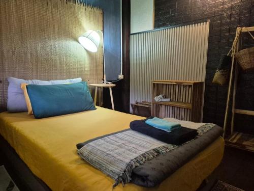 a bedroom with a yellow bed with blue pillows at Baan Koody Hostel
