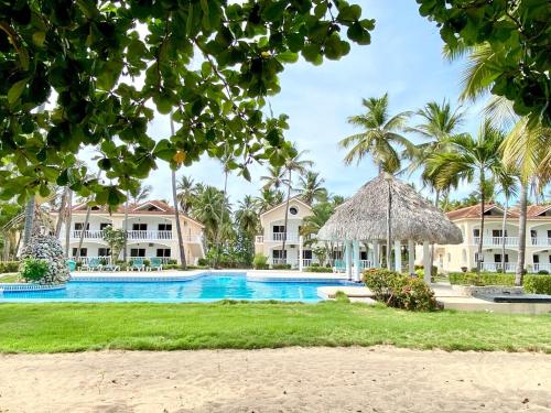 a resort swimming pool with palm trees and houses at Beautiful second floor apartment with loft 5D in El Francés