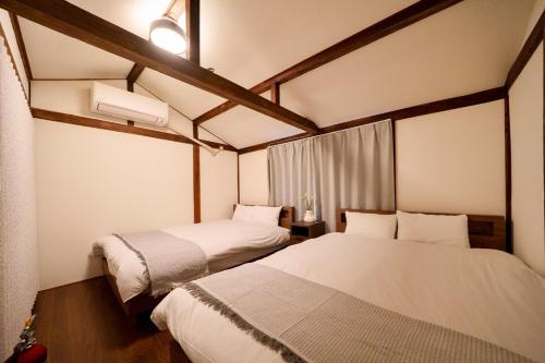 ein Schlafzimmer mit 2 Betten und einem Fenster und Avertisation in der Unterkunft Sen Yokohama 2K house near Bandobashi Sta 横浜阪東橋 in Yokohama