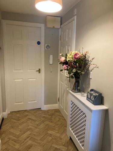 a hallway with a white door and a vase of flowers at The Eaves, Glastonbury High Street 2 bed 2 bathroom apartment in Glastonbury