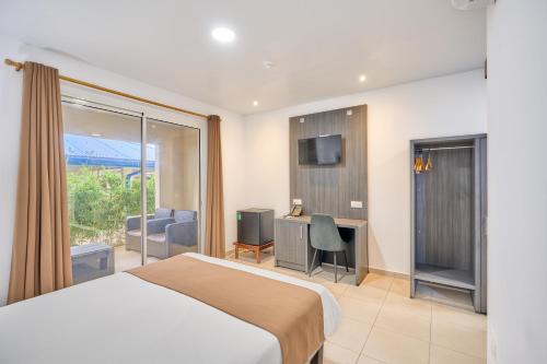 um quarto com uma cama, uma escrivaninha e uma televisão em Domaine du lac bleu em Saint-Laurent du Maroni