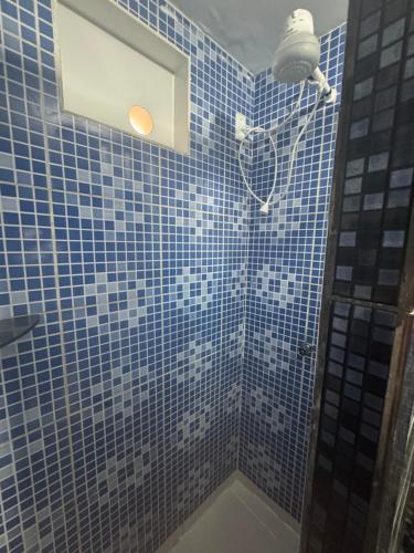 a bathroom with blue tiled walls and a shower with a window at Pousada Beleleuss in Jericoacoara