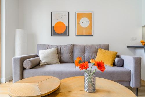 Una sala de estar con un sofá y una mesa con flores. en ShortStayPoland Zdziechowskiego, en Varsovia