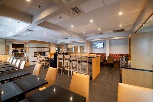 a restaurant with tables and chairs and a bar at Hôtel & Suites Le Dauphin Québec in Quebec City