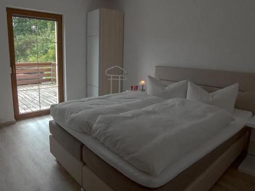 ein Schlafzimmer mit einem großen weißen Bett mit einem Fenster in der Unterkunft Ferienwohnung in Bad Elster mit Grill, Terrasse und Garten in Bad Elster