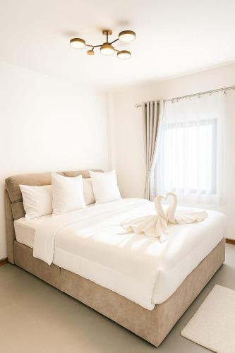 ein weißes Schlafzimmer mit einem großen Bett mit einer Blume darauf in der Unterkunft Wasana Village Phutoei in Ban Phu Toei